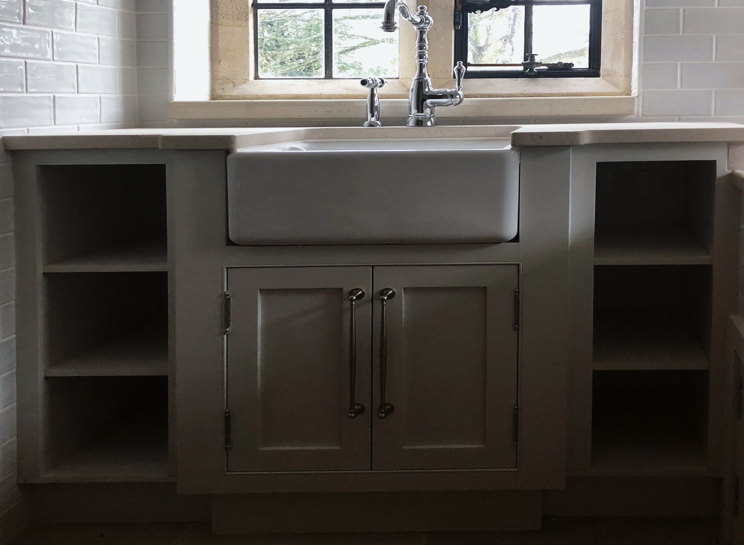 A low painted unit housing a deep sink, with open shelves either side