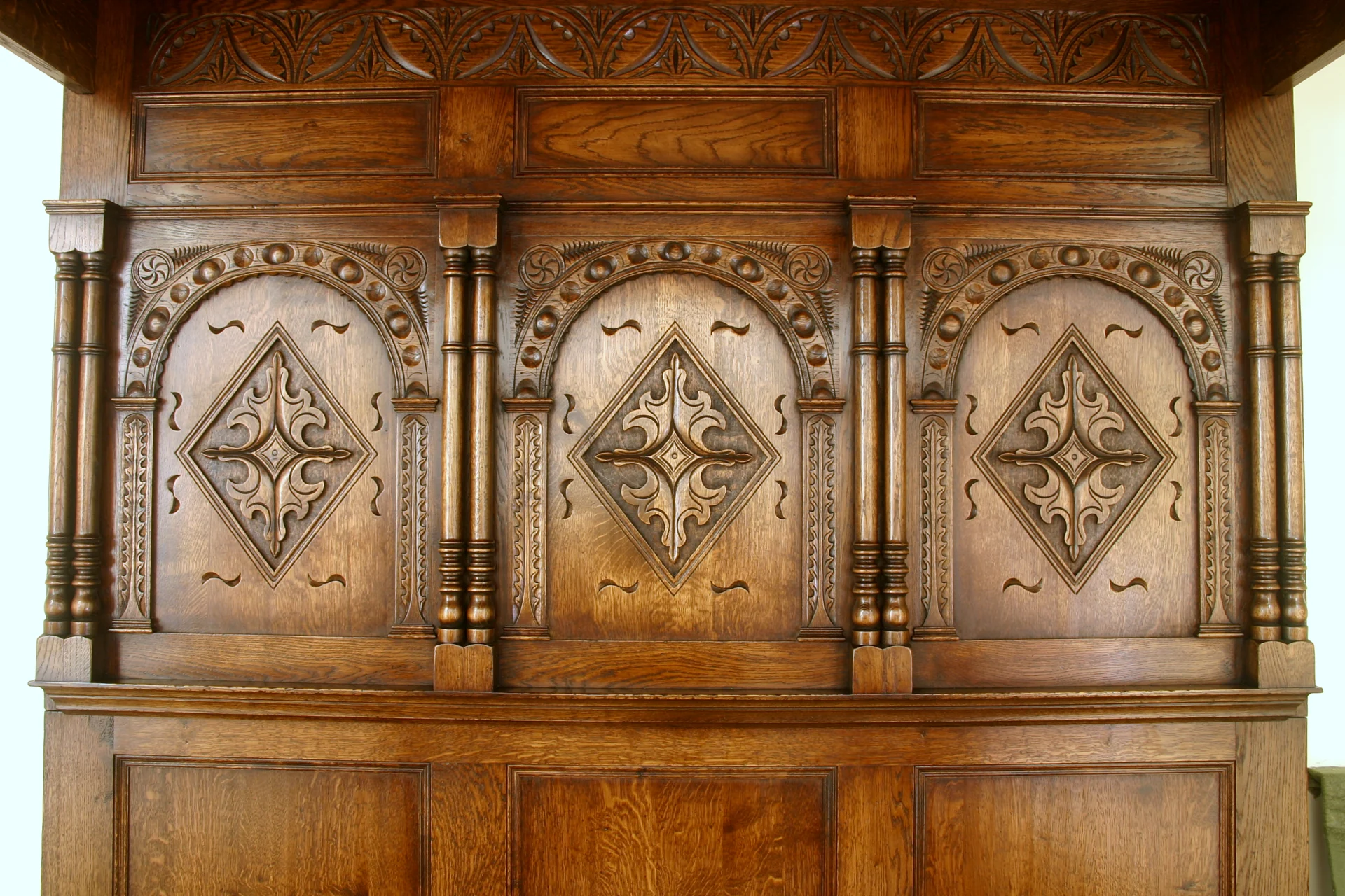 Hand-carved arcaded panels on an oak bed back board, made to order by Bryn Hall