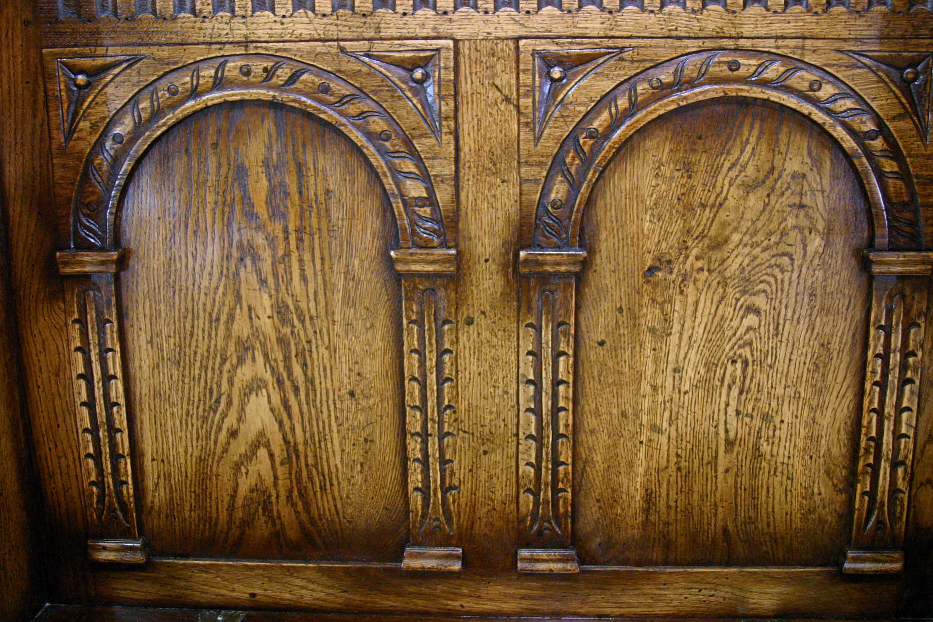 Two hand-carved arched panels in solid oak on a settle back, cut by hand at the Mickfield workshop