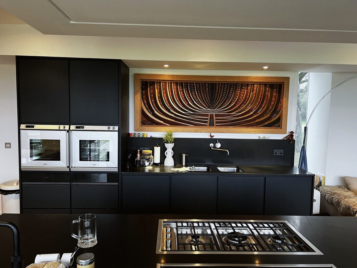 The cooking wall in matt black, with the marquetry panel above