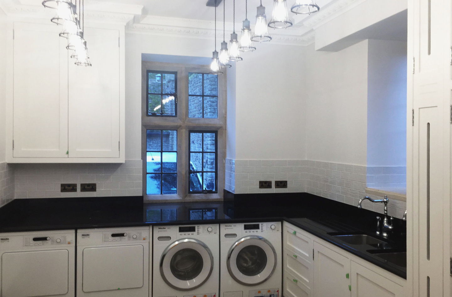 Washing machine and dryer housed under a stone top, painted doors alongside